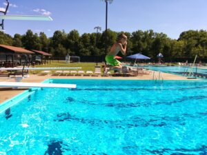 Kid jumping from the diving board into a pool